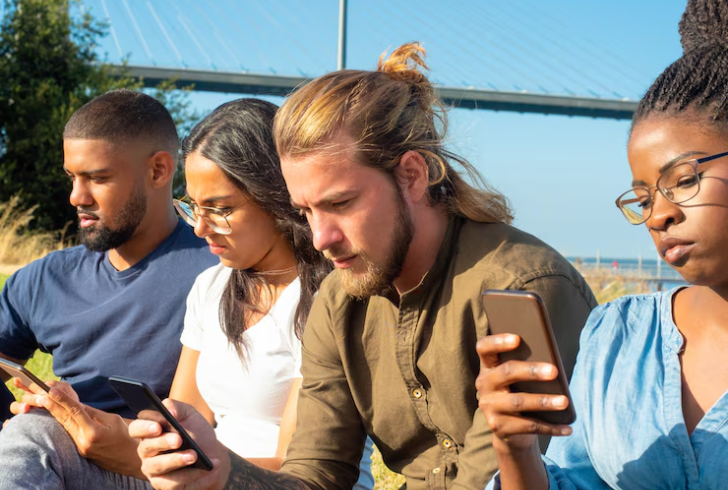 A group of young adults chatting on their phones together in a casual setting